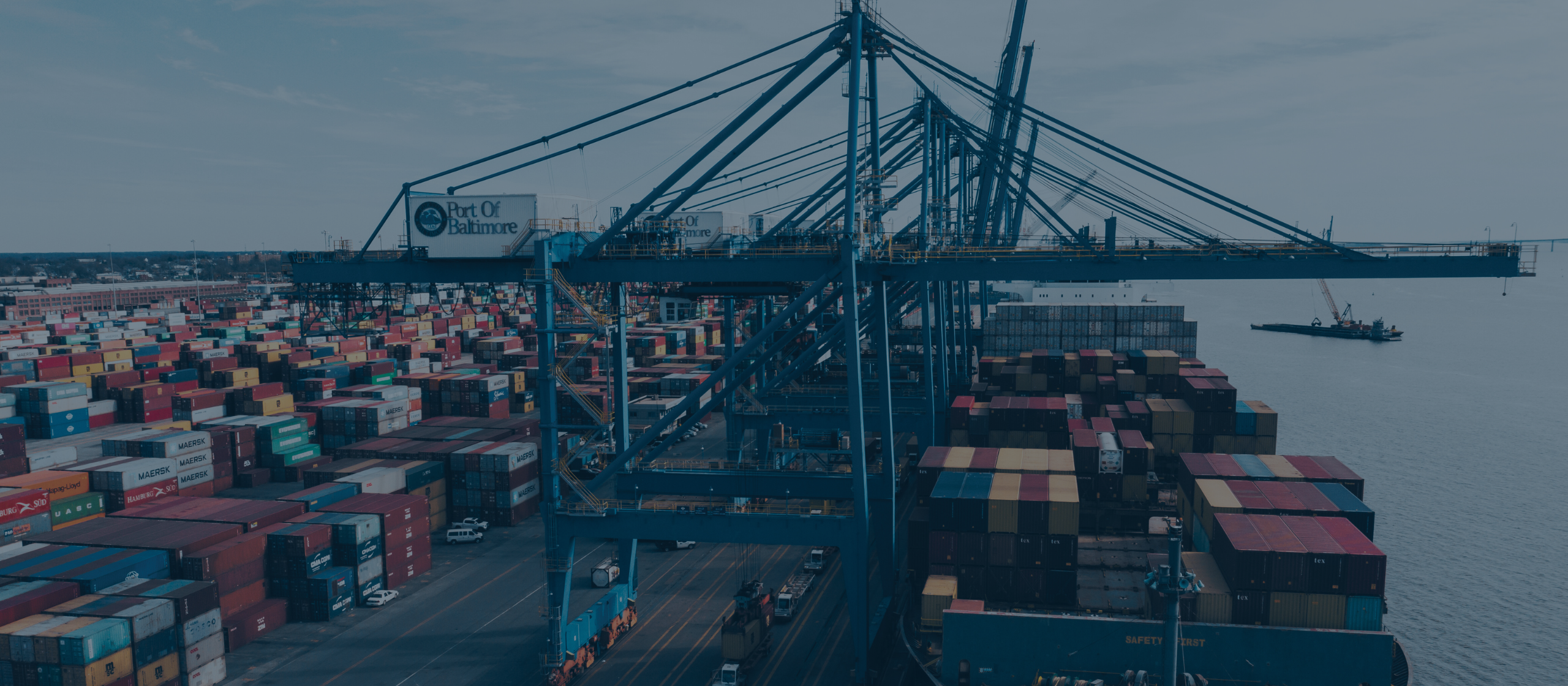 Photo of freight containers and cranes by a body of water